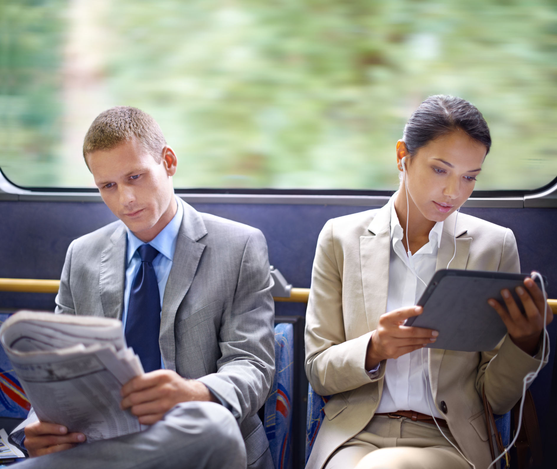 Two business people reading catching up on the news on their commute to work